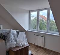 PREDAJ – 4-izbový rodinný dom v radovej zástavbe s garážou - Podkrovná izba s veľkým oknom, radiátorom a podlahou s dreveným dekorom.