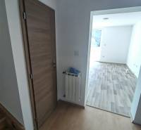 PREDAJ – 4-izbový rodinný dom v radovej zástavbe s garážou - Interiér rodinného domu s dverami, radiátorom a podlahou s dreveným dekorom.