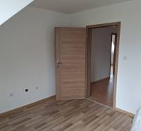 PREDAJ – 4-izbový rodinný dom v radovej zástavbe s garážou - Izba v Rodinnom dome s podlahou s dreveným dekorom a drevenými dverami.