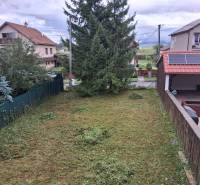PREDAJ – 4-izbový rodinný dom v radovej zástavbe s garážou - Záhrada pri rodinnom dome v Ľubeli s udržiavaným trávnikom a hustými stromami.