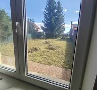 PREDAJ – 4-izbový rodinný dom v radovej zástavbe s garážou - Pohľad z rodinného domu v Ľubeli do záhrady s udržiavaným trávnikom a stromami.