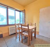 Pôvodný domček v obci Nová Vieska - Jedáleň v rodinnom dome s jednoduchým dreveným stolom a stoličkami, žlté steny.