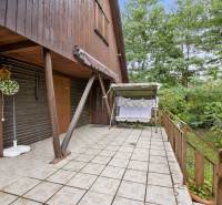 NA PREDAJ CHATA V REKREAČNEJ OBLASTI RUDAVA, OBEC MALÉ LEVÁRE - Terasa pri chate v Malých Levároch s hojdacou lavicou a bohatou zeleňou.