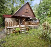 NA PREDAJ CHATA V REKREAČNEJ OBLASTI RUDAVA, OBEC MALÉ LEVÁRE - Chata v Malých Levároch s kamennou terasou obklopená zeleňou a stromami.