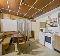 NA PREDAJ CHATA V REKREAČNEJ OBLASTI RUDAVA, OBEC MALÉ LEVÁRE - Interiér chaty s kuchynským kútom, rohovou lavicou a jedálenským stolom.