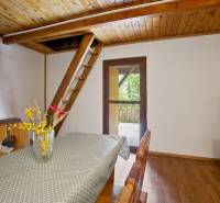 NA PREDAJ CHATA V REKREAČNEJ OBLASTI RUDAVA, OBEC MALÉ LEVÁRE - Jedálenský stôl s kvetmi, schody na poschodie, podlaha s dreveným dekorom.