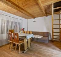 NA PREDAJ CHATA V REKREAČNEJ OBLASTI RUDAVA, OBEC MALÉ LEVÁRE - Interiér chaty s dreveným schodiskom, jedálenským stolom a podlahou s dreveným dekorom.