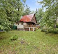 NA PREDAJ CHATA V REKREAČNEJ OBLASTI RUDAVA, OBEC MALÉ LEVÁRE - Chata v Malých Levároch obklopená zeleňou, s červenou strechou a drevenými prvkami.