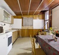 NA PREDAJ CHATA V REKREAČNEJ OBLASTI RUDAVA, OBEC MALÉ LEVÁRE - Kuchyňa v Chate s kuchynskou linkou, stolom a stoličkami, podlaha s dreveným dekorom.