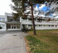 Prenájom ordinácie v zdravotnom stredisku Saratovská 24, Bratislava. - Biela budova a zeleň na ulici Saratovská, obchodné priestory v Bratislave - Dúbravka.