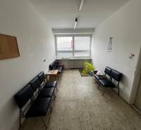 Prenájom ordinácie v zdravotnom stredisku Saratovská 24, Bratislava. - Čakáreň s čiernymi stoličkami, detským kútikom a svetlou podlahou v obchodných priestoroch.