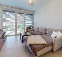 RADO I 2-izbový byt 49m² s terasou 71m² I Soblahov - Obývačka v 2-izbovom byte s pohodlným gaučom a veľkými oknami.