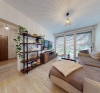 RADO I 2-izbový byt 49m² s terasou 71m² I Soblahov - Obývačka v 2-izbovom byte s pohodlnou sedačkou a podlahou s dreveným dekorom.