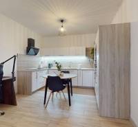 RADO I 2-izbový byt 49m² s terasou 71m² I Soblahov - Kuchyňa v 2-izbovom byte s policami, podlahou s dreveným dekorom a pracovným kútom.