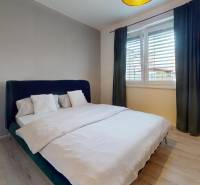 RADO I 2-izbový byt 49m² s terasou 71m² I Soblahov - Spálňa s veľkou posteľou, svetlými stenami a podlahou s dreveným dekorom v 2-izbovom byte.