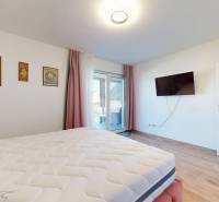 MALÉ LEVÁRE-Predaj  3i modernej novostavby RD s tep. čerpadlom + garáž - Spálňa v rodinnom dome s podlahou s dreveným dekorom a televízorom na stene.