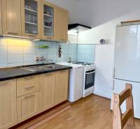 PRENÁJOM 1 izbový byt, 40 M2, Bratislava, Ružinov, Košická ulica, NIVY - Kuchyňa v 1-izbovom byte s dreveným dekorom, kuchynskou linkou a spotrebičmi.