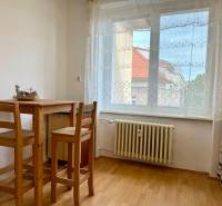 PRENÁJOM 1 izbový byt, 40 M2, Bratislava, Ružinov, Košická ulica, NIVY - Jedálenský kút so stolom z dreva, podlaha s dreveným dekorom, záclona na okne.