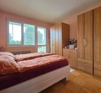 REZERVOVANÉ - Priestranný 4-izbový byt, 84m2 + loggia – Terasa - Spálňa s posteľou, skriňami a podlahou s dreveným dekorom v 4-izbovom byte.