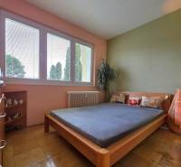 REZERVOVANÉ - Priestranný 4-izbový byt, 84m2 + loggia – Terasa - Spálňa v 4-izbovom byte s veľkým oknom a podlahou s dreveným dekorom.