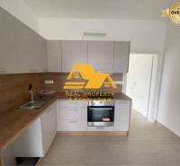 Prenajmem zariadený 3 izbový byt v Nových Zámkoch - Kuchyňa v 3-izbovom byte s dreveným dekorom pracovnej dosky a bielymi skrinkami.