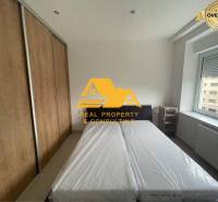 Prenajmem zariadený 3 izbový byt v Nových Zámkoch - Spálňa v 3-izbovom byte s posteľou, vstavanou skriňou a oknom s výhľadom.