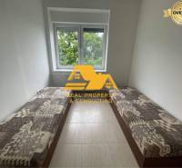 Prenajmem zariadený 3 izbový byt v Nových Zámkoch - Útulná izba v 3-izbovom byte s dvoma postelemi a výhľadom na zeleň.