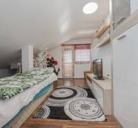 2-Generačný 9izb. RD s bazénom a veľkým pozemkom, Dvorníky - Podkrovná izba v rodinnom dome s posteľou, TV, dekoráciami a podlahou s dreveným dekorom.