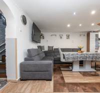 2-Generačný 9izb. RD s bazénom a veľkým pozemkom, Dvorníky - Obývačka s rohovou sedačkou, stolom a podlahou s dreveným dekorom v rodinnom dome.