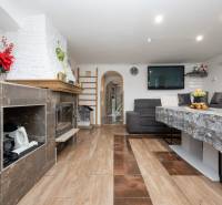 2-Generačný 9izb. RD s bazénom a veľkým pozemkom, Dvorníky - Obývacia izba s krbom, sedacou súpravou a stolom; podlaha s dreveným dekorom.