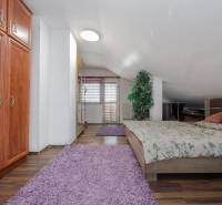 2-Generačný 9izb. RD s bazénom a veľkým pozemkom, Dvorníky - Spálňa v rodinnom dome s posteľou, skriňou a podlahou s dreveným dekorom.