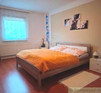 Veľkorysý 10-árový pozemok, slnečná nehnuteľnosť, priestranné bývanie  - Spálňa v rodinnom dome s posteľou, dekoráciou a podlahou s dreveným dekorom.