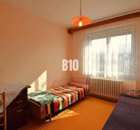 5 izbový  rodinný dom vo Varíne - Izba v rodinnom dome s jednoduchým nábytkom, posteľou a oranžovým lampášom.