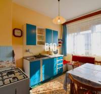 5 izbový  rodinný dom vo Varíne - Kuchyňa v rodinnom dome s modrou linkou, plynovým sporákom a jedálenským stolom.