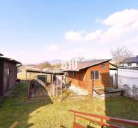 5 izbový  rodinný dom vo Varíne - Záhrada pri rodinnom dome v Žiline s drevenou prístavbou a výhľadom na krajinu.