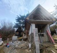RO Domaša Zajačia Debra - Chata pri vode! - Stavba chaty na Zajačej debre v Holčíkovciach obklopená stromami a stavebným materiálom.