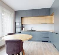 Predaj, 3-izbový byt v Slnečniciach, Bratislava - Kuchyňa s modernou linkou, okrúhlym stolom a podlahou s dreveným dekorom v 3-izbovom byte.