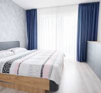 Predaj, 3-izbový byt v Slnečniciach, Bratislava - Spálňa v 3-izbovom byte s posteľou, modrými závesmi a komodou.