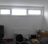 Obchodný priestor na prenájom pri ceste o ploche  372 m2  - Izba s oknom a kancelárskymi stoličkami v obchodných priestoroch.
