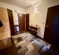 3 izbový byt  Topoľčany blízko centra - Predsieň s tmavými dverami, komodou, a podlahou s dreveným dekorom v 3-izbovom byte.