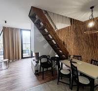 Luxusná Apartmánová chata Domaša Eva: Airbnb Hit! - Chata s podlahou s dreveným dekorom, schodiskom a stolom vedľa steny z drevených lamiel.