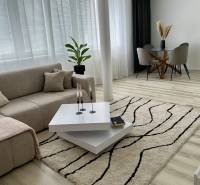 - PRENÁJOM - 2 IZBOVÝ BYT - DOLNÁ UL. - STARÉ MESTO - Svetlá obývačka s pohovkou, konferenčným stolíkom, jedálenským stolom a podlahou s dreveným dekorom.