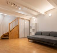 Priestranný 4-izbový byt s predzáhradkou, Staré Mesto - Obývacia izba s pohovkou a schodiskom, podlaha s dreveným dekorom, 4-izbový byt.