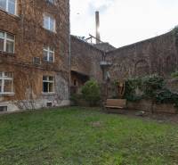 Priestranný 4-izbový byt s predzáhradkou, Staré Mesto - Dvor obytného domu na Medenej ulici v Bratislave - Staré Mesto s lavičkou a zeleňou.