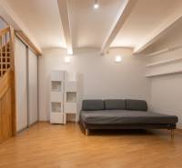 Priestranný 4-izbový byt s predzáhradkou, Staré Mesto - Obývacia izba s pohovkou, schodmi a podlahou s dreveným dekorom v 4-izbovom byte.