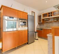 Priestranný 4-izbový byt s predzáhradkou, Staré Mesto - Kuchyňa v 4-izbovom byte s nerezovým spotrebičmi a drevenými skrinkami.