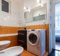 Priestranný 4-izbový byt s predzáhradkou, Staré Mesto - Kúpeľňa so vstavanou práčkou a oranžovým obkladom v 4-izbovom byte.