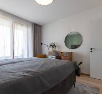 2-izbový byt s lodžiou v projekte Zwirn - Spálňa s posteľou, zrkadlom a komodou, na podlahe s dreveným dekorom v 2-izbovom byte.