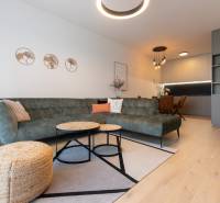 2-izbový byt s lodžiou v projekte Zwirn - Obývacia izba v 2-izbovom byte s pohovkou, konferenčnými stolíkmi a podlahou s dreveným dekorom.