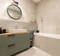 2-izbový byt s lodžiou v projekte Zwirn - Kúpeľňa v 2-izbovom byte s vaňou, umývadlom a okrúhlym zrkadlom na stene.